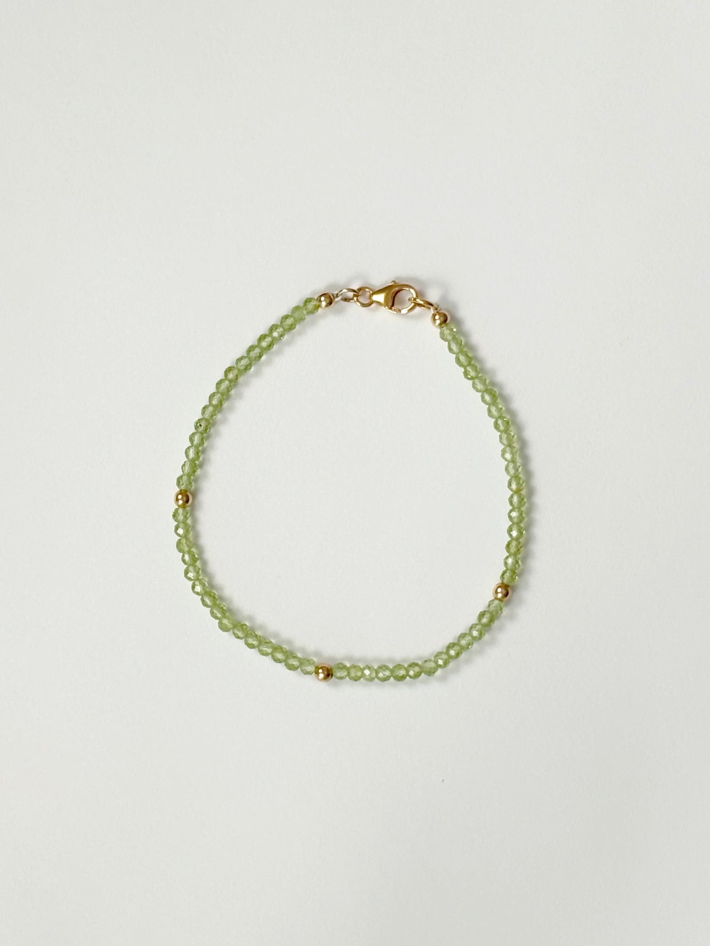 Green beaded bracelet on a light gray background