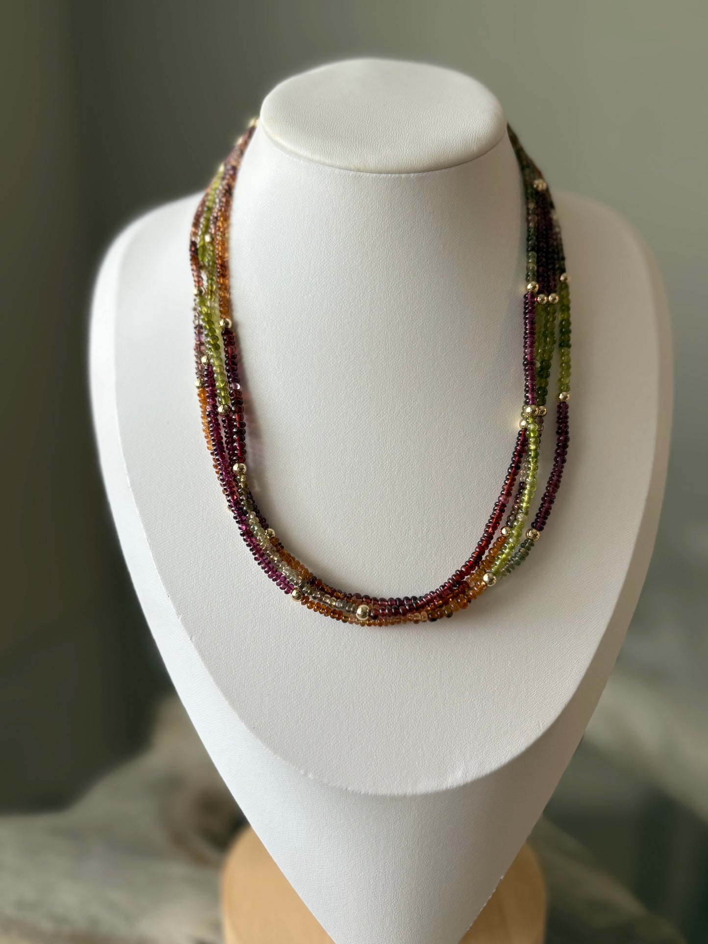 Sapphire Necklace with multiple strands of green, purple, and orange beads with gold accents