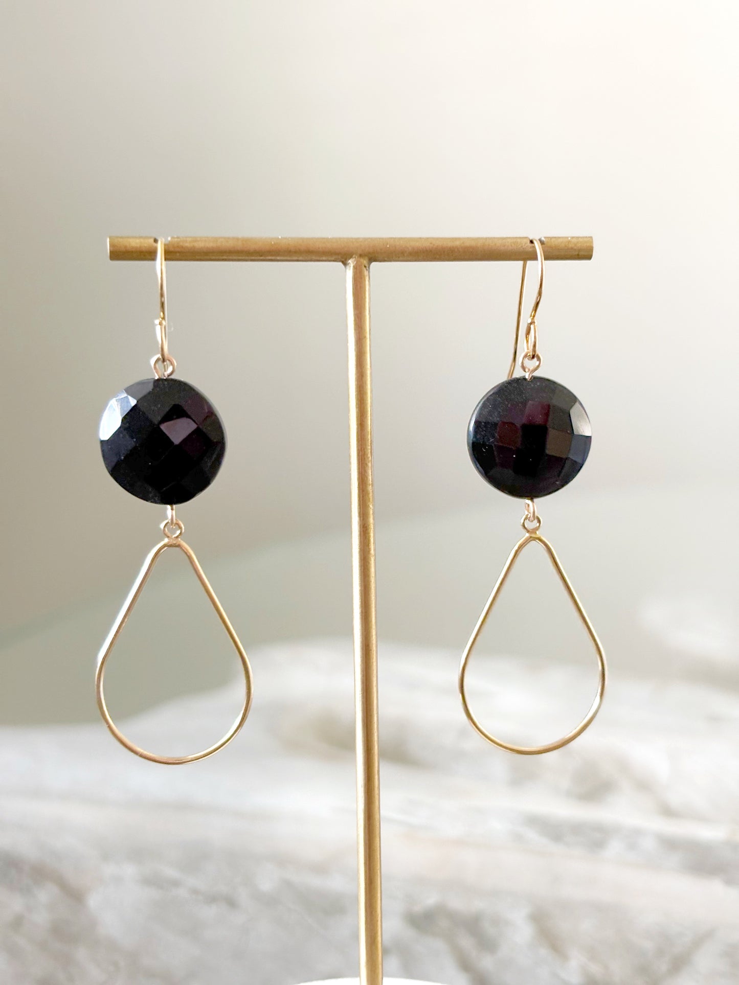 Black Onyx Gold Drop Earrings on a gold display stand