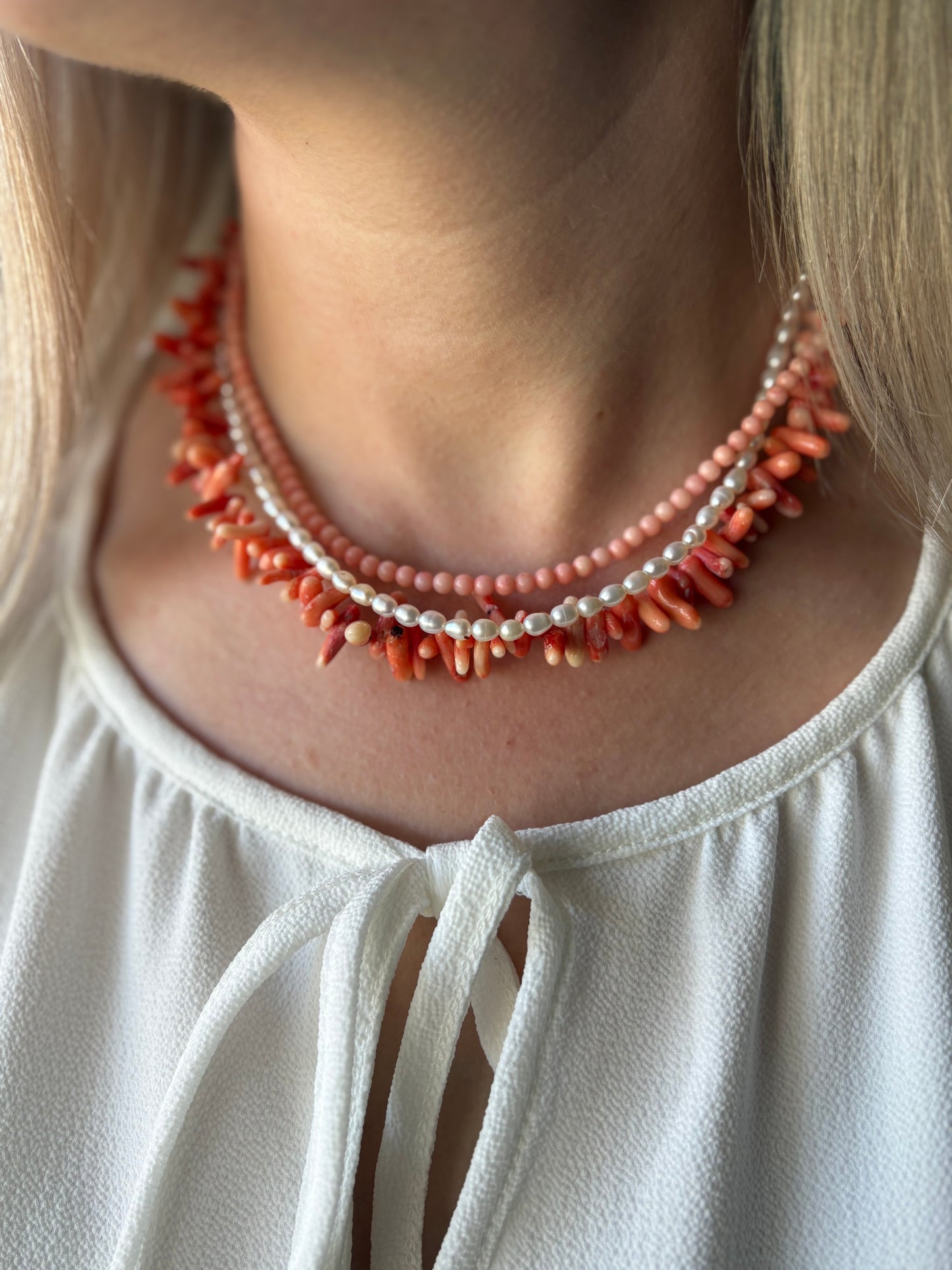 Multi Strand Coral and Pearl Necklace on a person wearing a white top