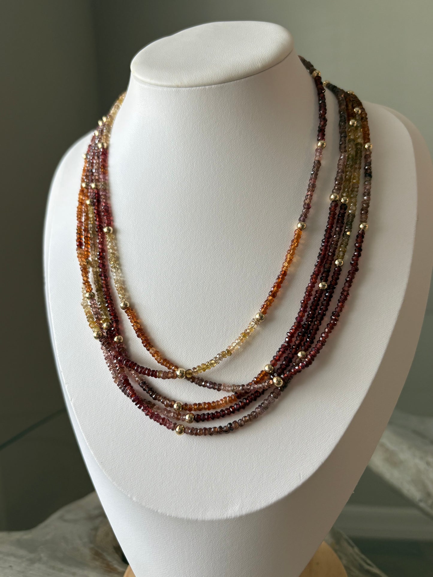 Sapphire Necklace with multiple strands of faceted beads in shades of red, orange, and yellow, with gold beads