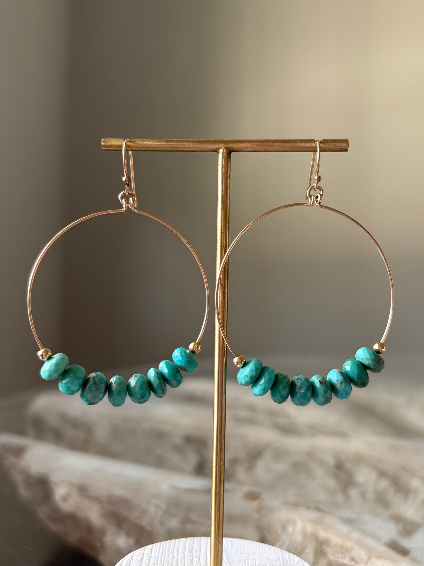 Turquoise XL Gold Hoop Earrings displayed on a gold earring stand