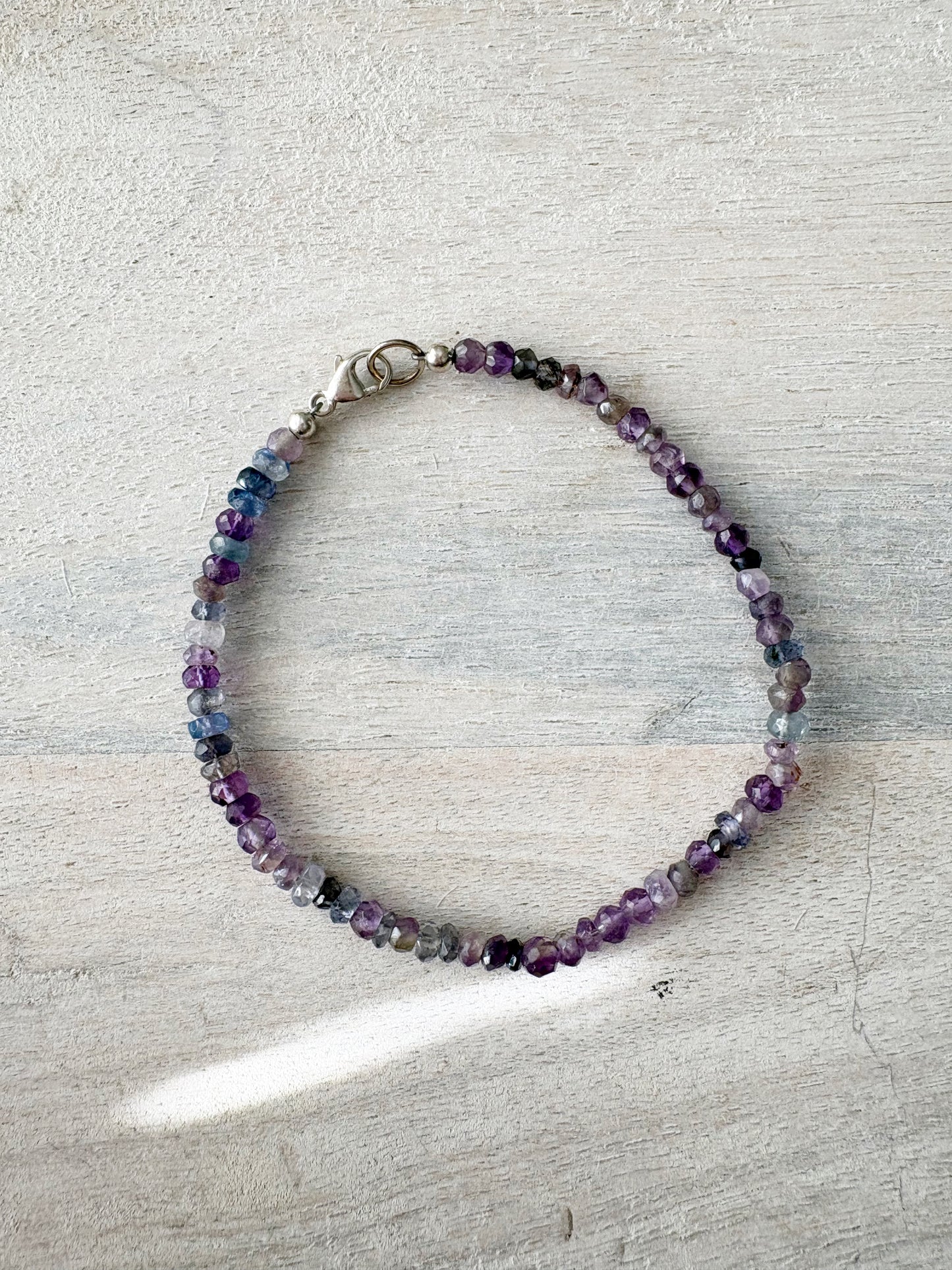Multi Purple Bracelet with small faceted purple, blue, and grey beads and a silver clasp