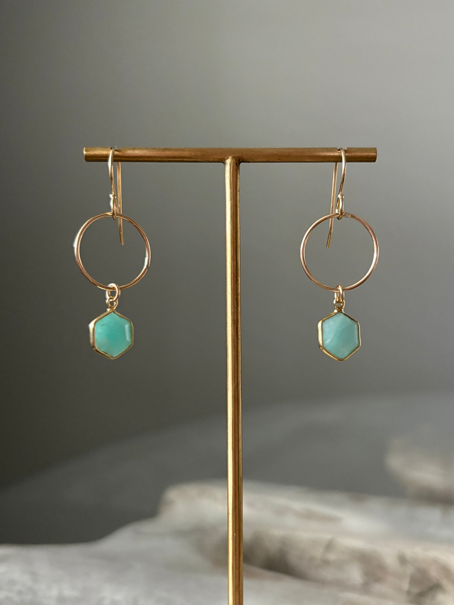Gold earrings with turquoise stones on a gray background