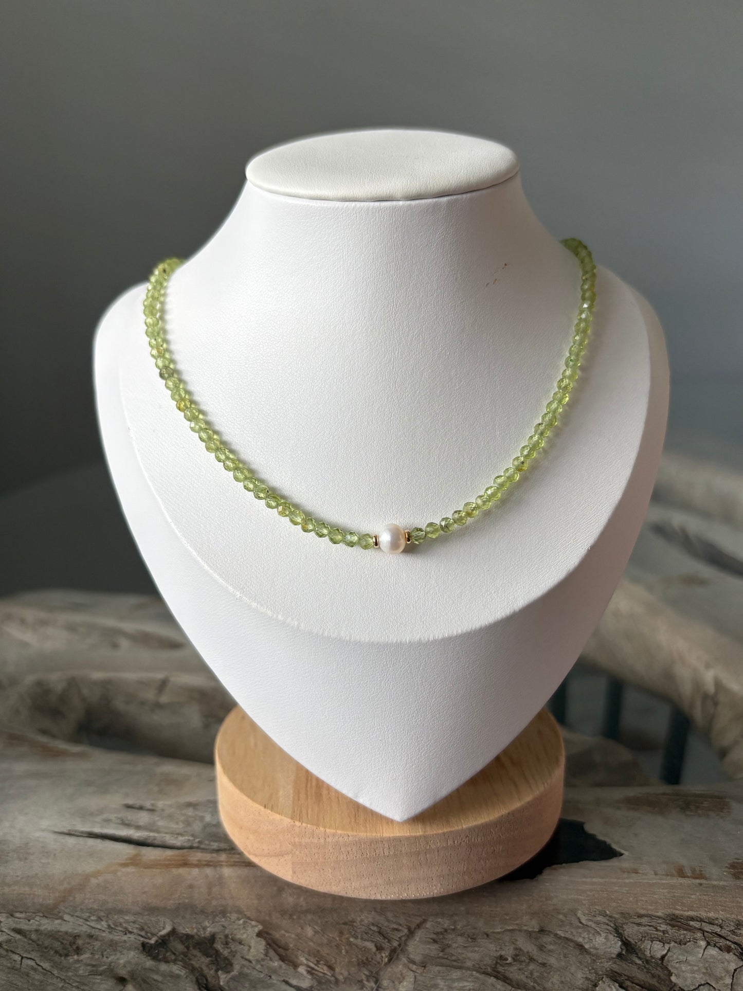 Peridot and Pearl Necklace on a white display stand