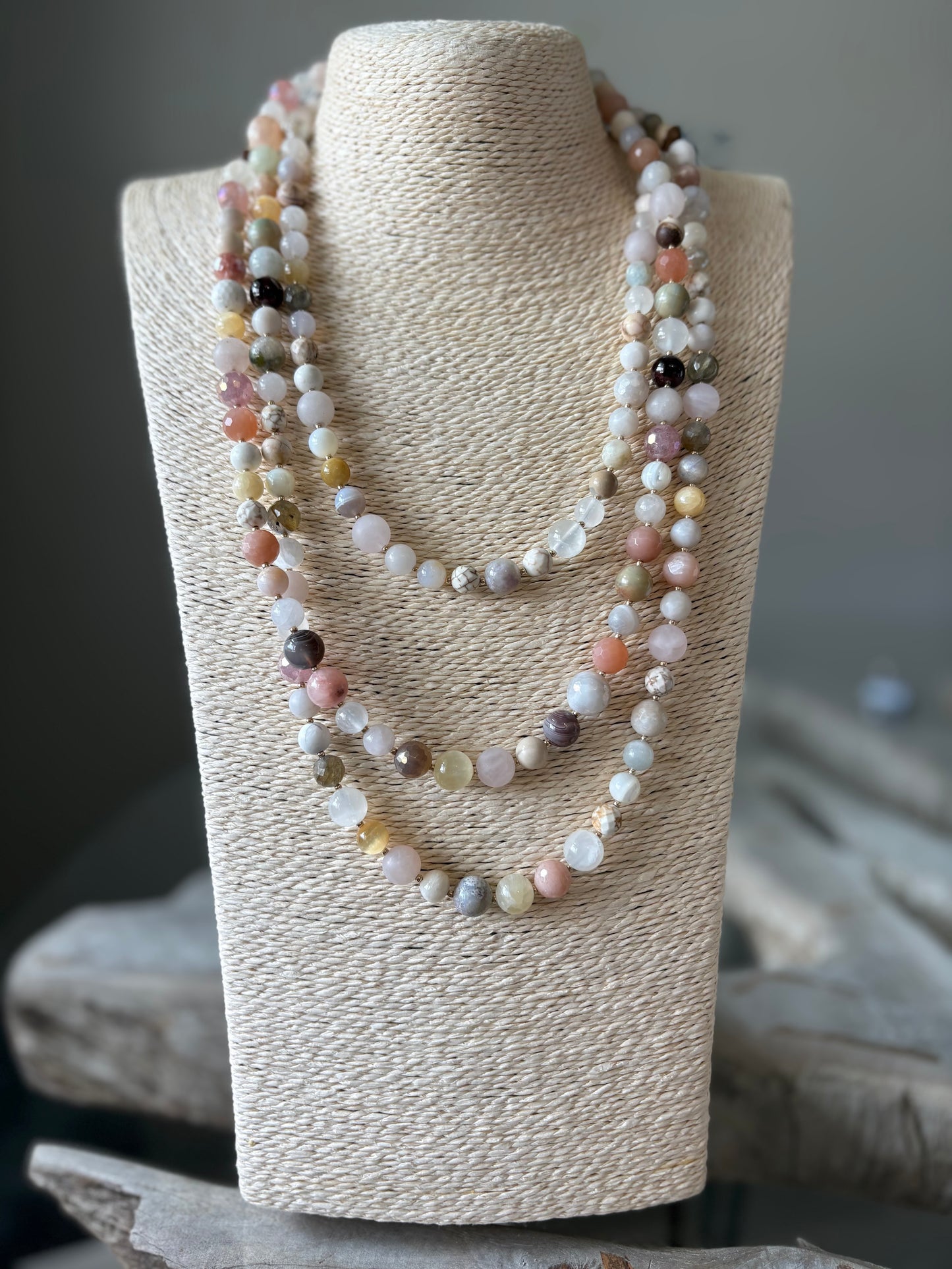 Multicolored beaded necklace on a textured beige stand with a blurred background
