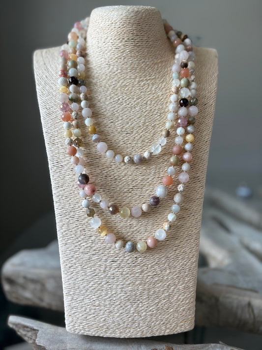Multicolored beaded necklace on a textured beige stand with a blurred background