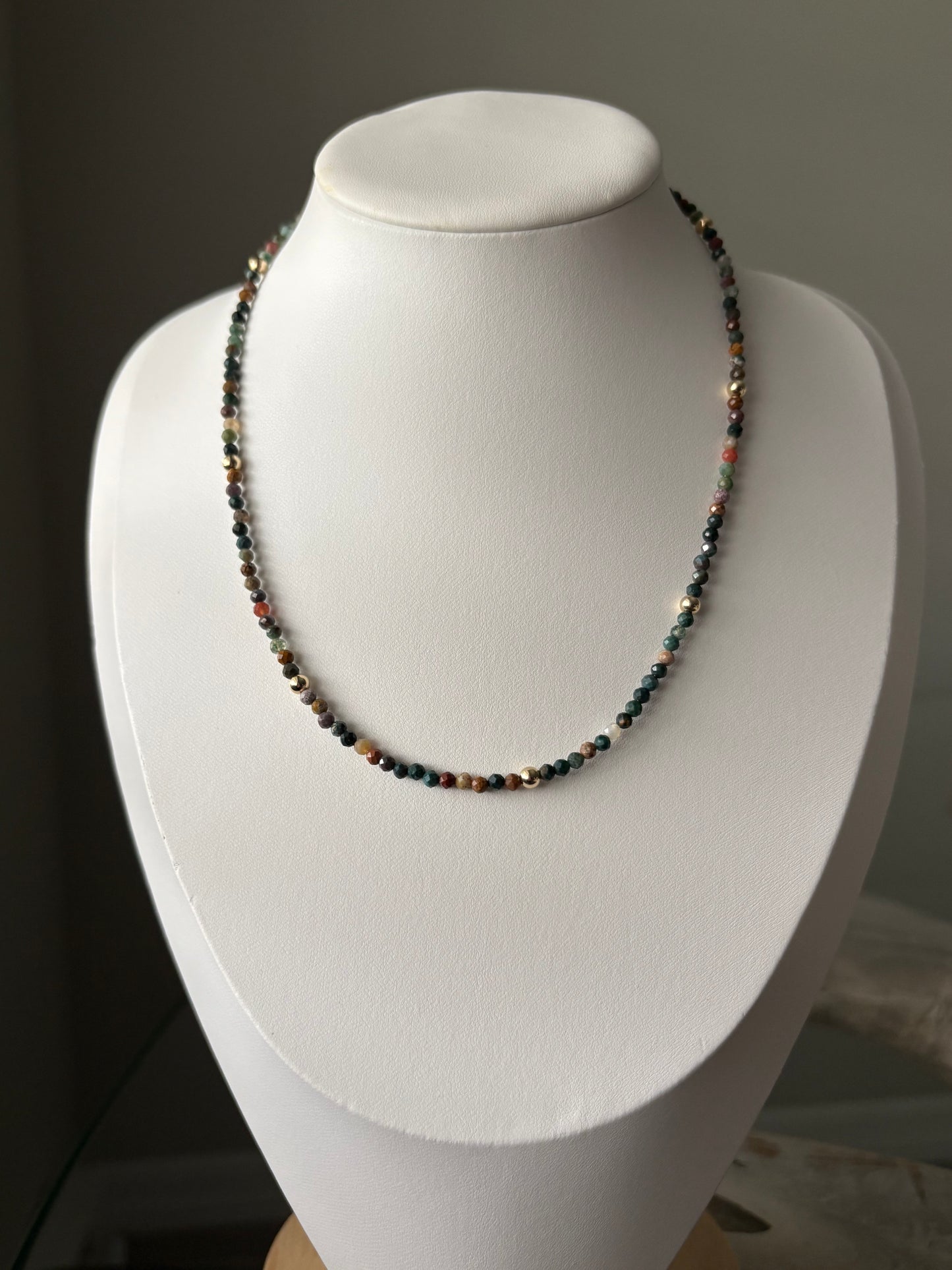 Indian Agate Gold Necklace with small, faceted, multicolored beads and gold accents on a white bust