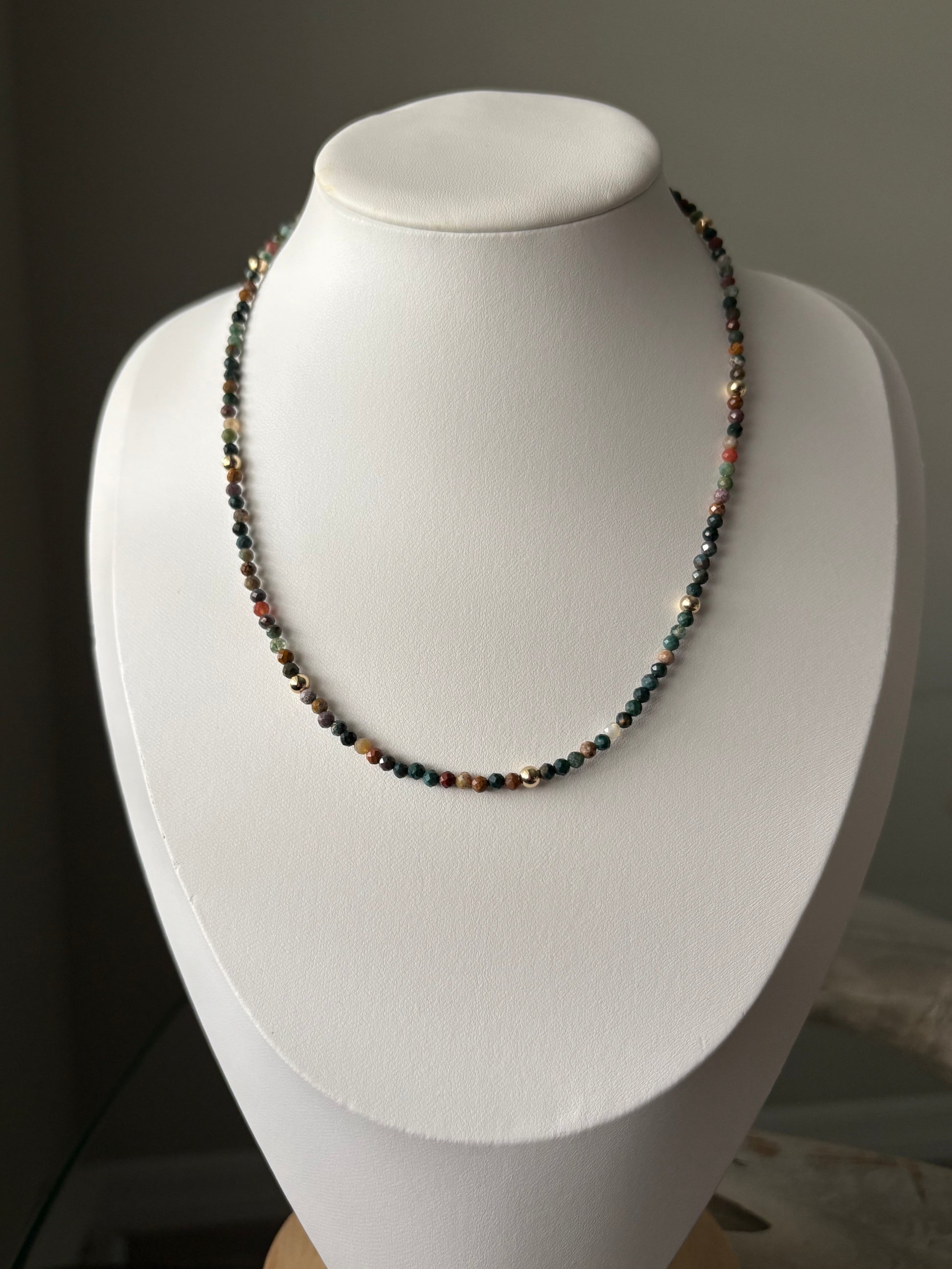 Indian Agate Gold Necklace with small, faceted, multicolored beads and gold accents on a white bust