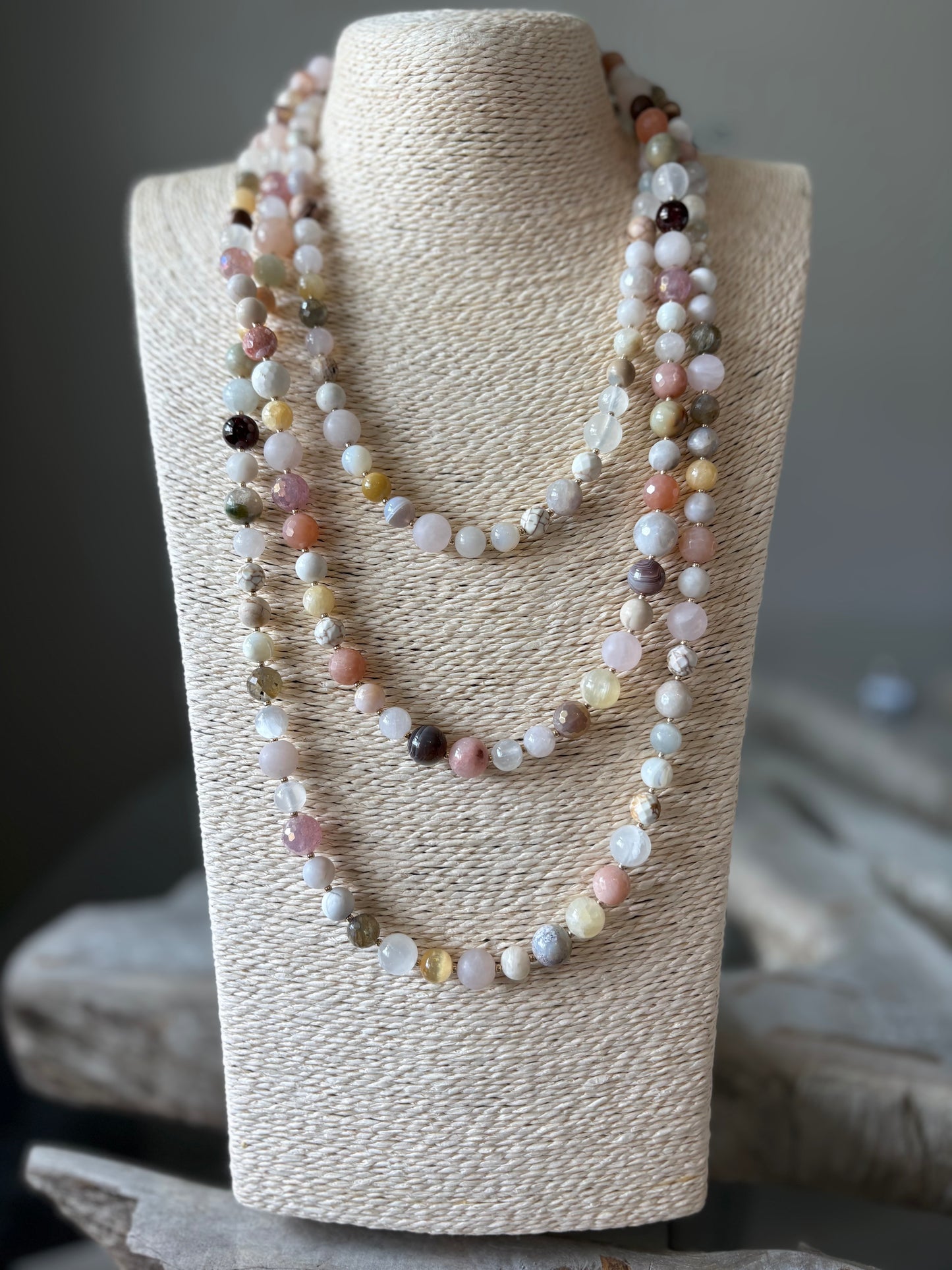 Necklace displayed on a textured white stand with a blurred background
