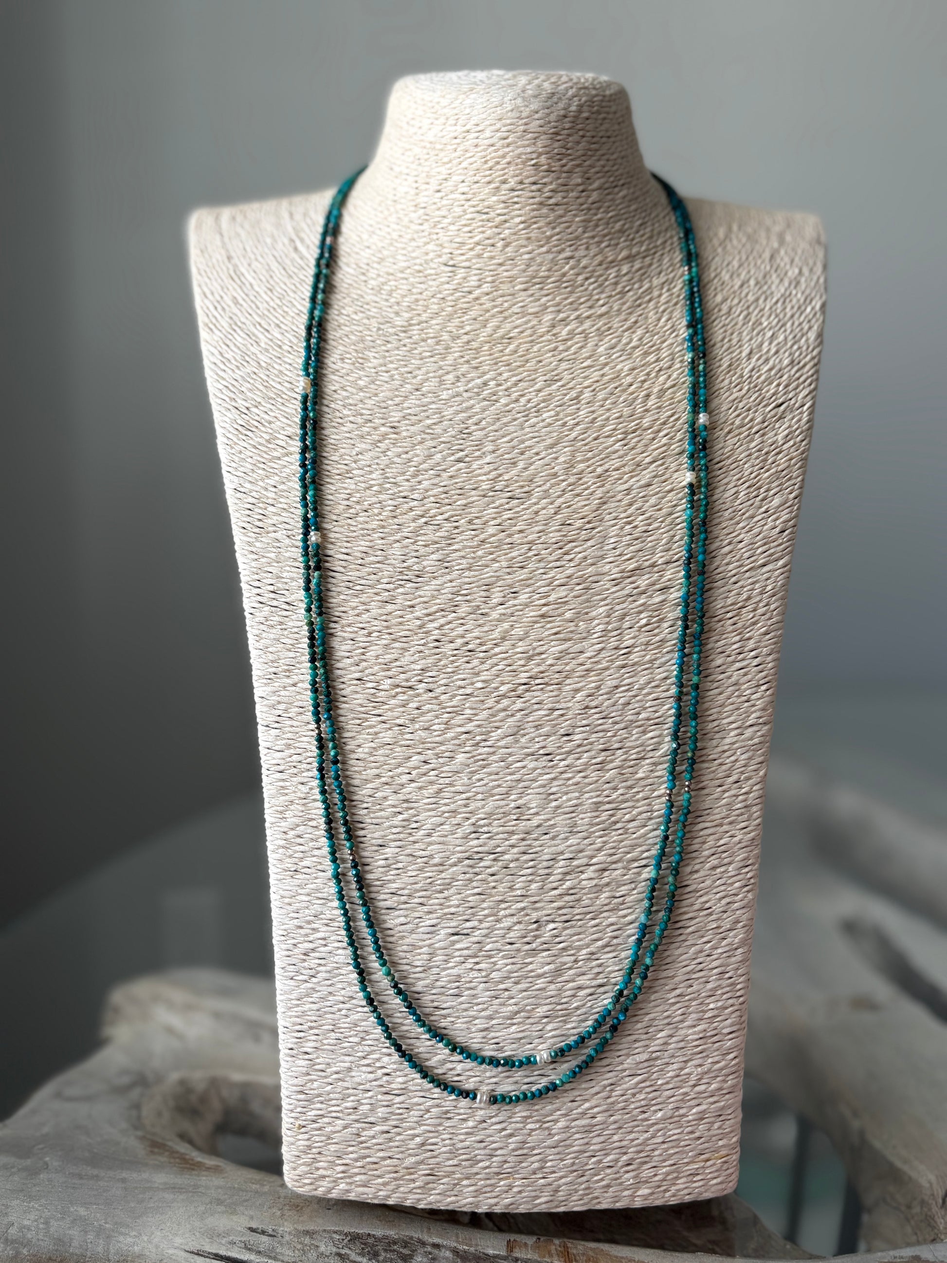 Long Chrysocolla Necklace with small turquoise beads and white pearls on a light-colored display bust