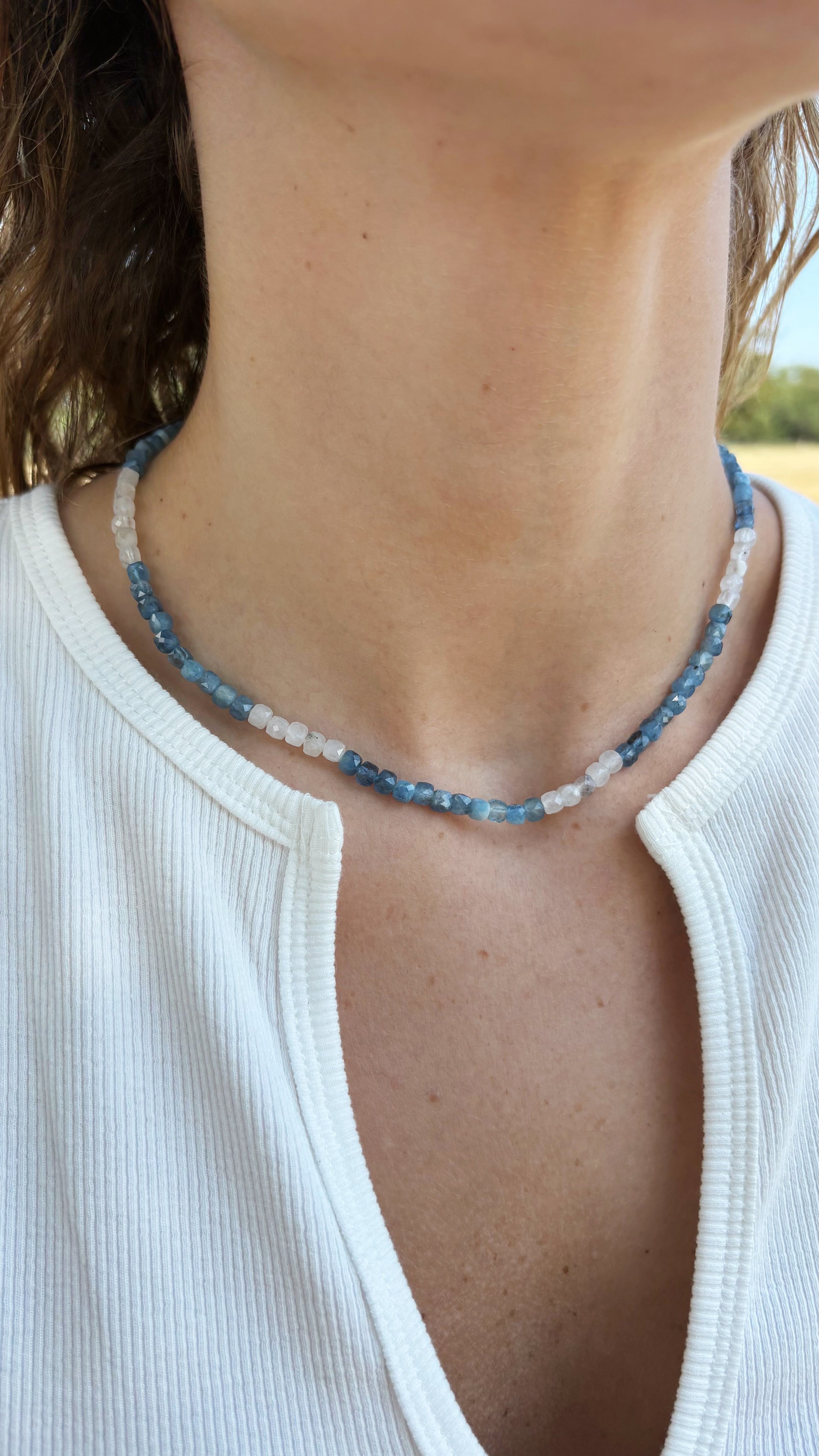 Aquamarine silver necklace featuring alternating blue and white faceted gemstone beads worn around the neck