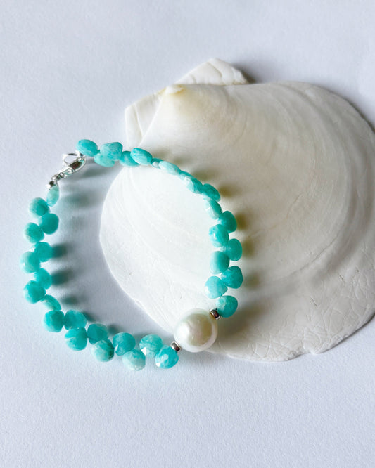 Turquoise beaded bracelet on a white shell against a light gray background