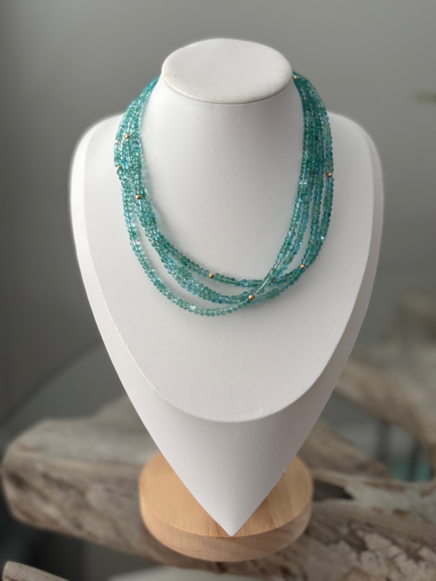 Turquoise beaded necklace on a white mannequin bust with a blurred background