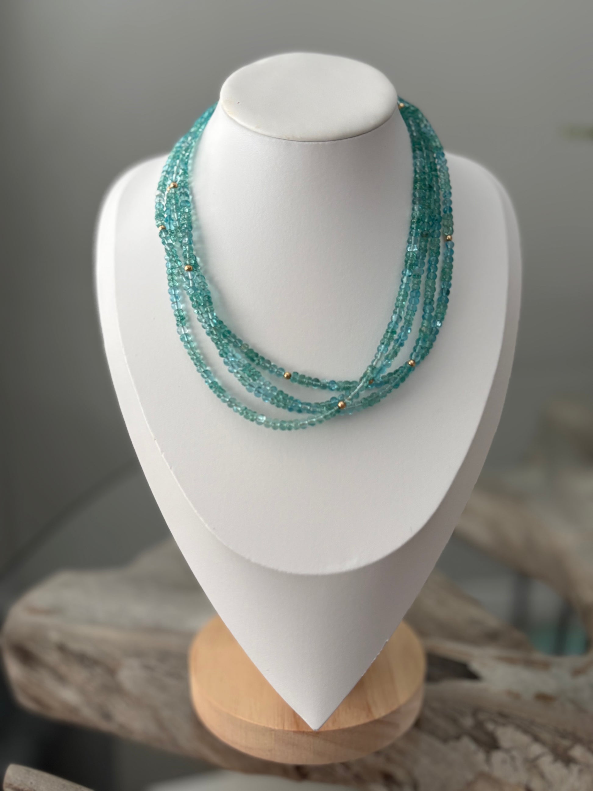 Turquoise beaded necklace on a white mannequin bust with a blurred background