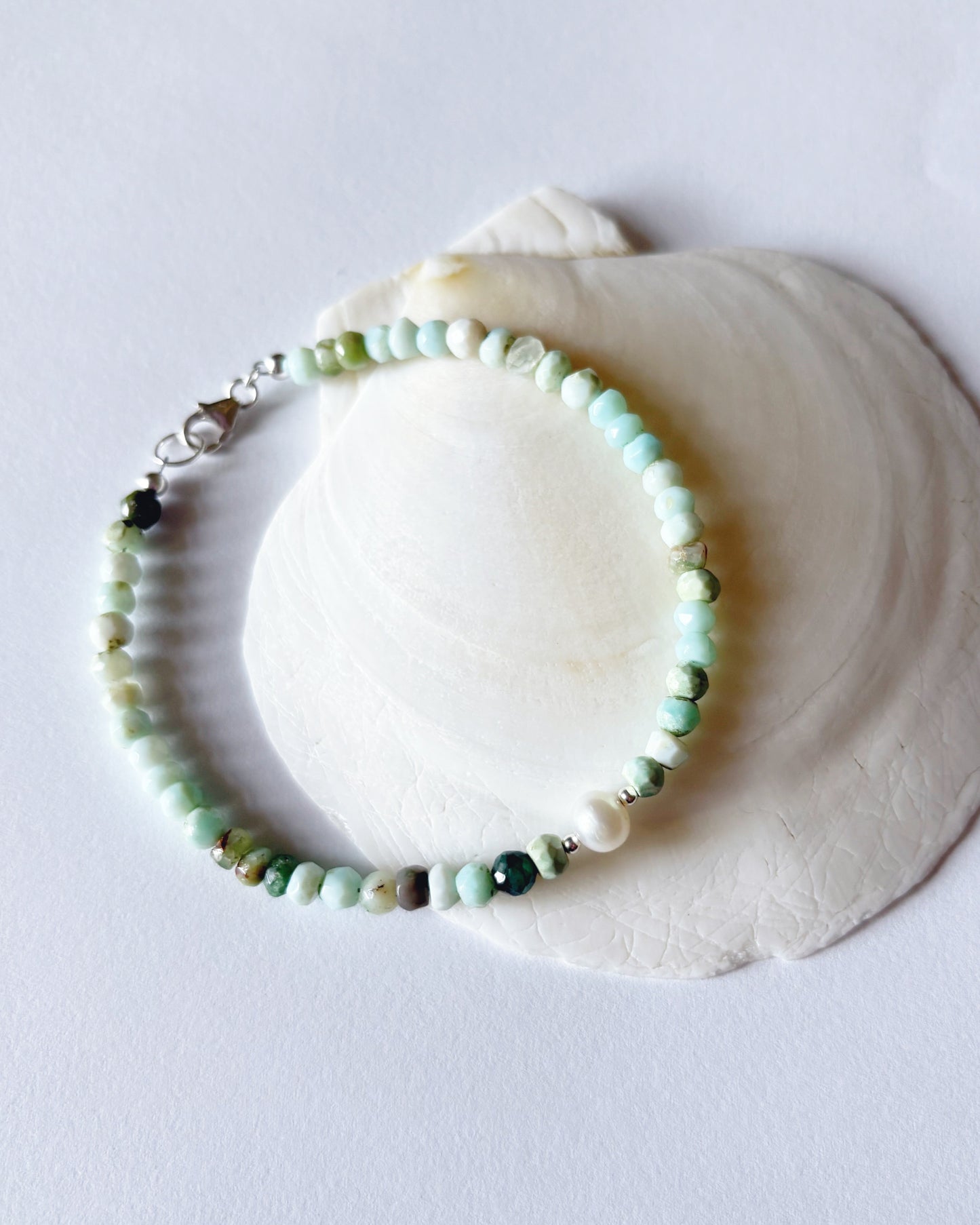 Beaded bracelet on a white shell against a light gray background