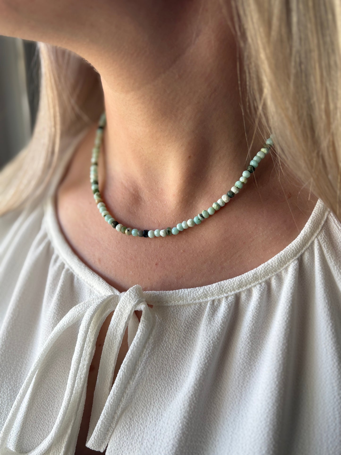 Peruvian Opal Gold Necklace with light blue, green, and black beads on a woman's neck