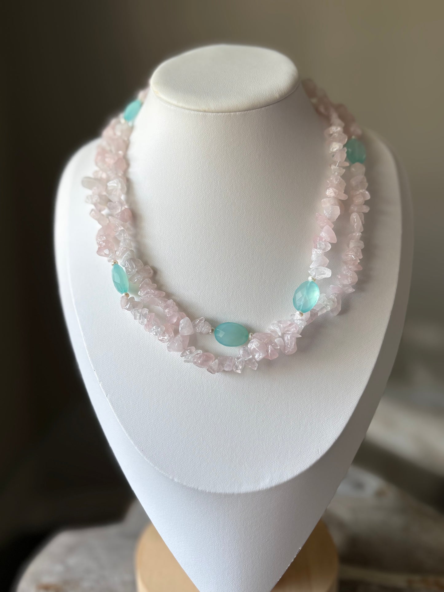 Necklace with pink and turquoise beads on a white mannequin bust.