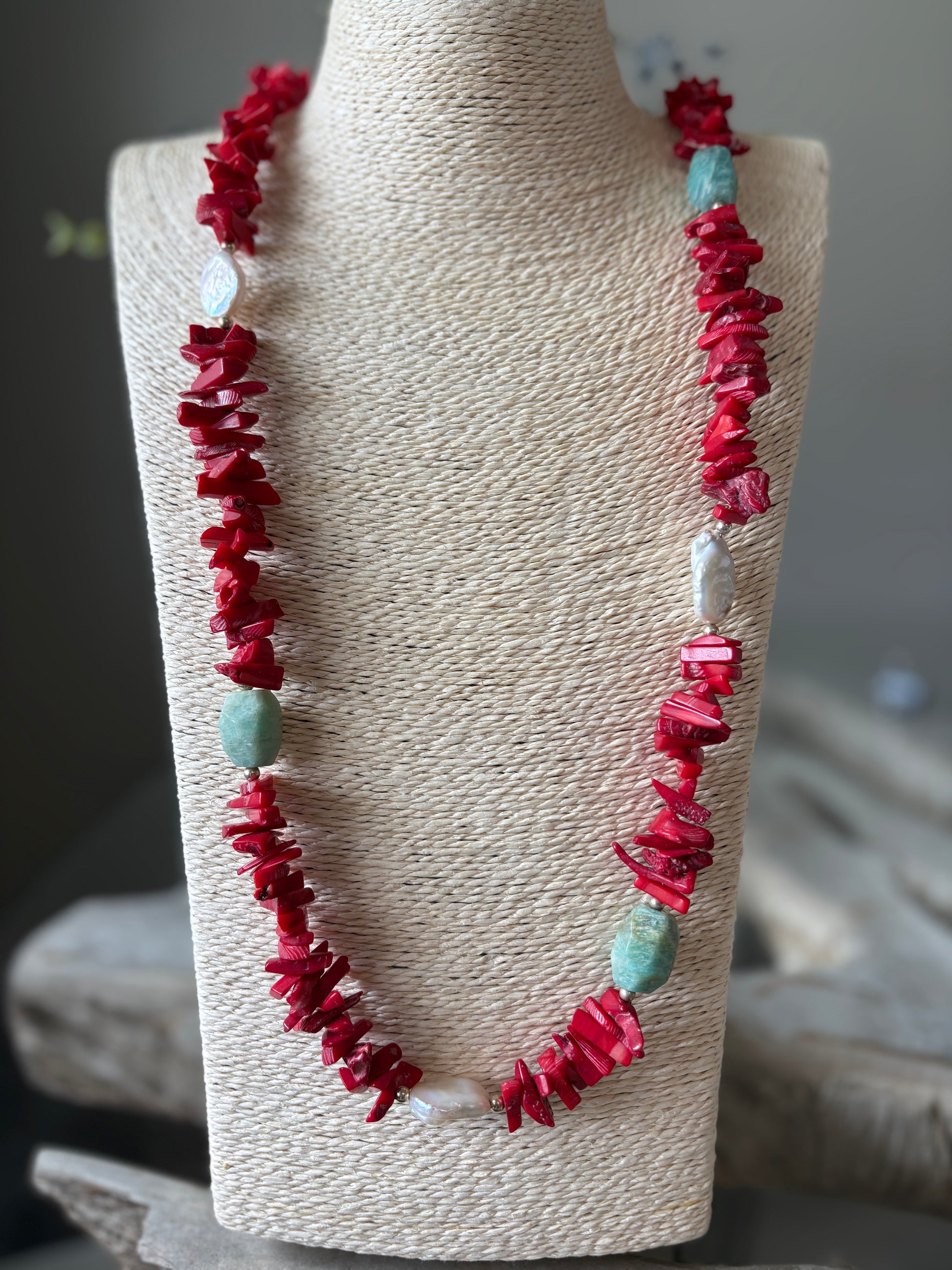 Necklace with red and turquoise beads on a mannequin bust.