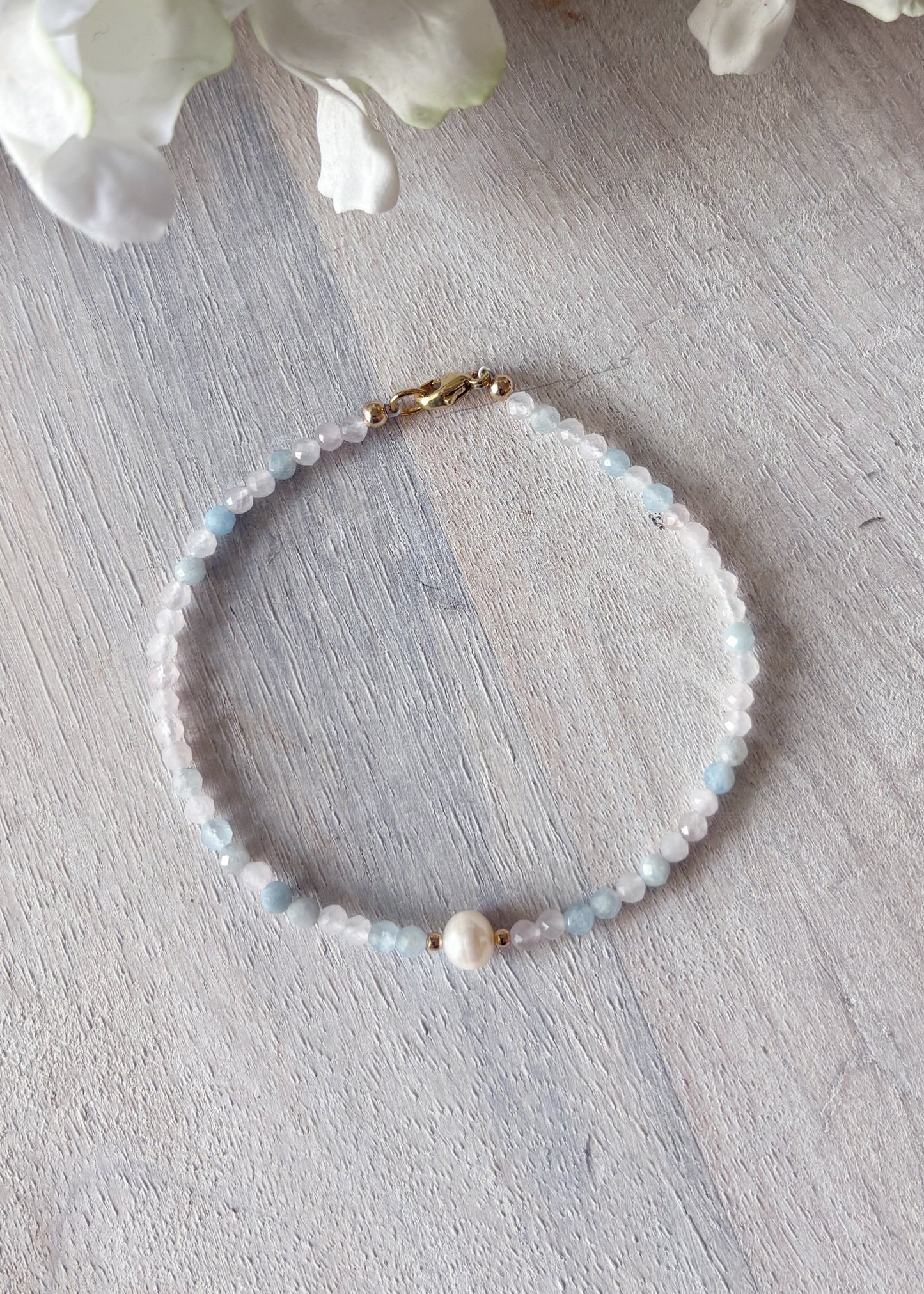 Beaded bracelet on a light wooden surface with white flowers in the background