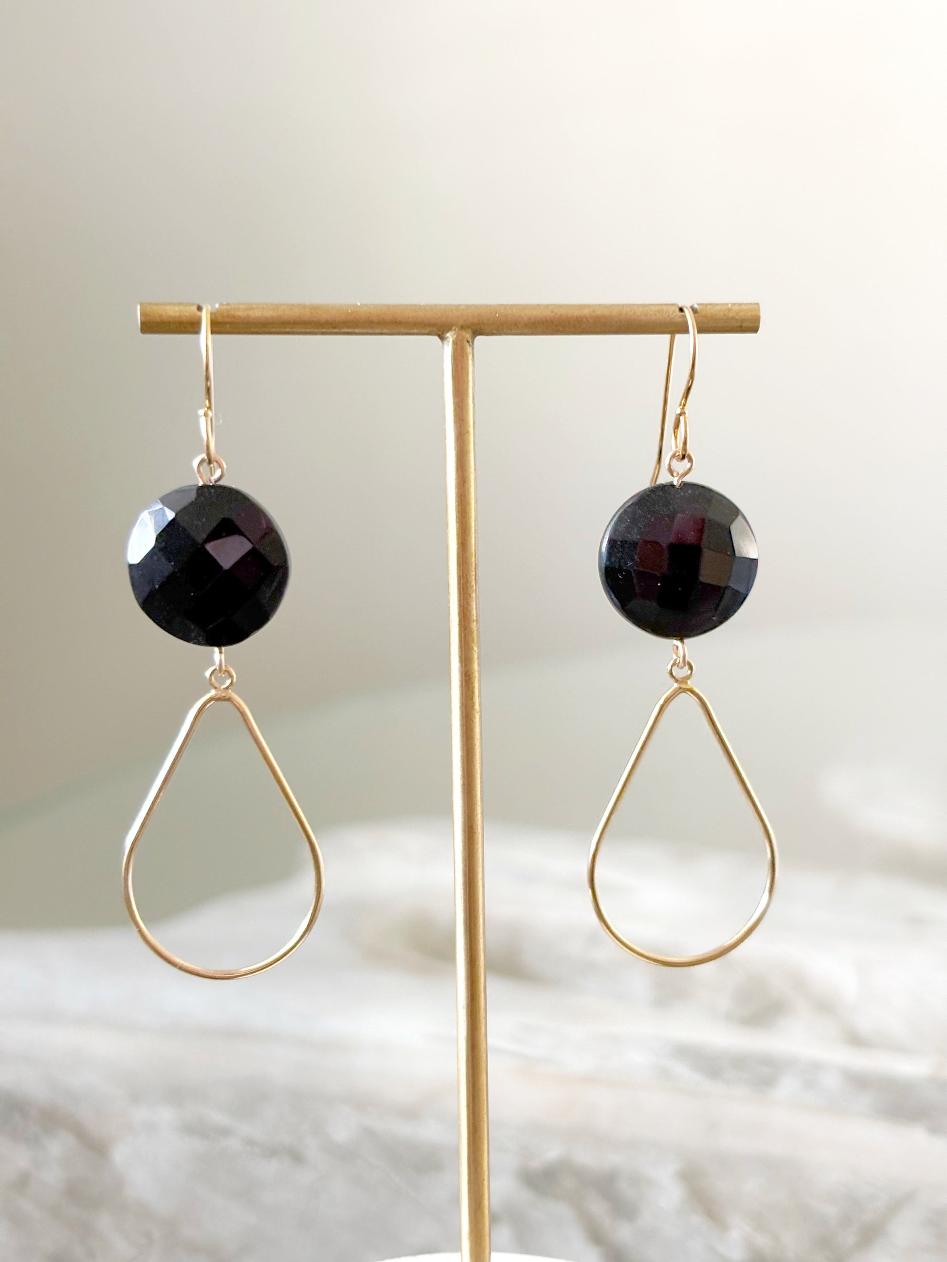 Black Onyx Gold Drop Earrings on a gold display stand