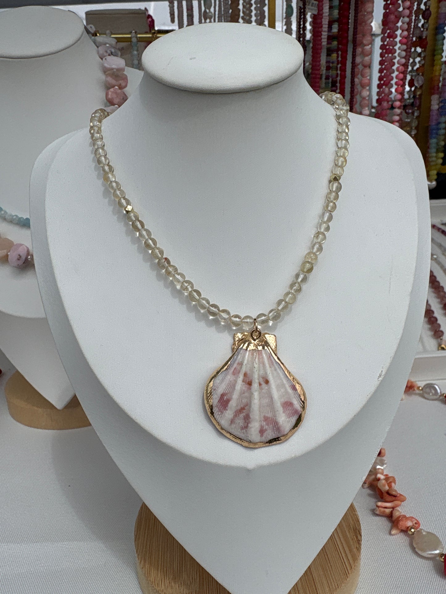 Citrine and pink shell necklace on a white display bust