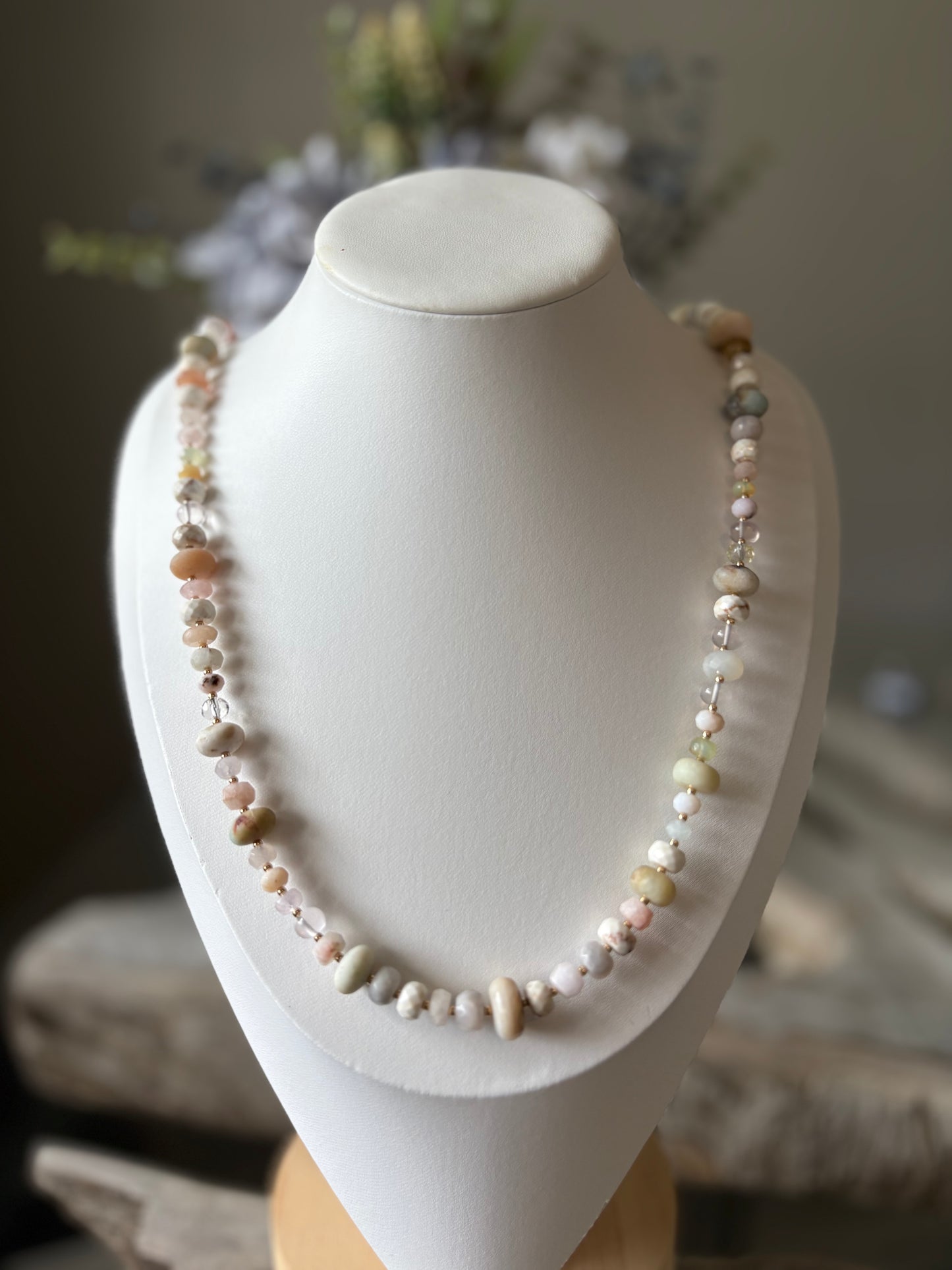 Necklace with multicolored beads on a white mannequin bust against a blurred background