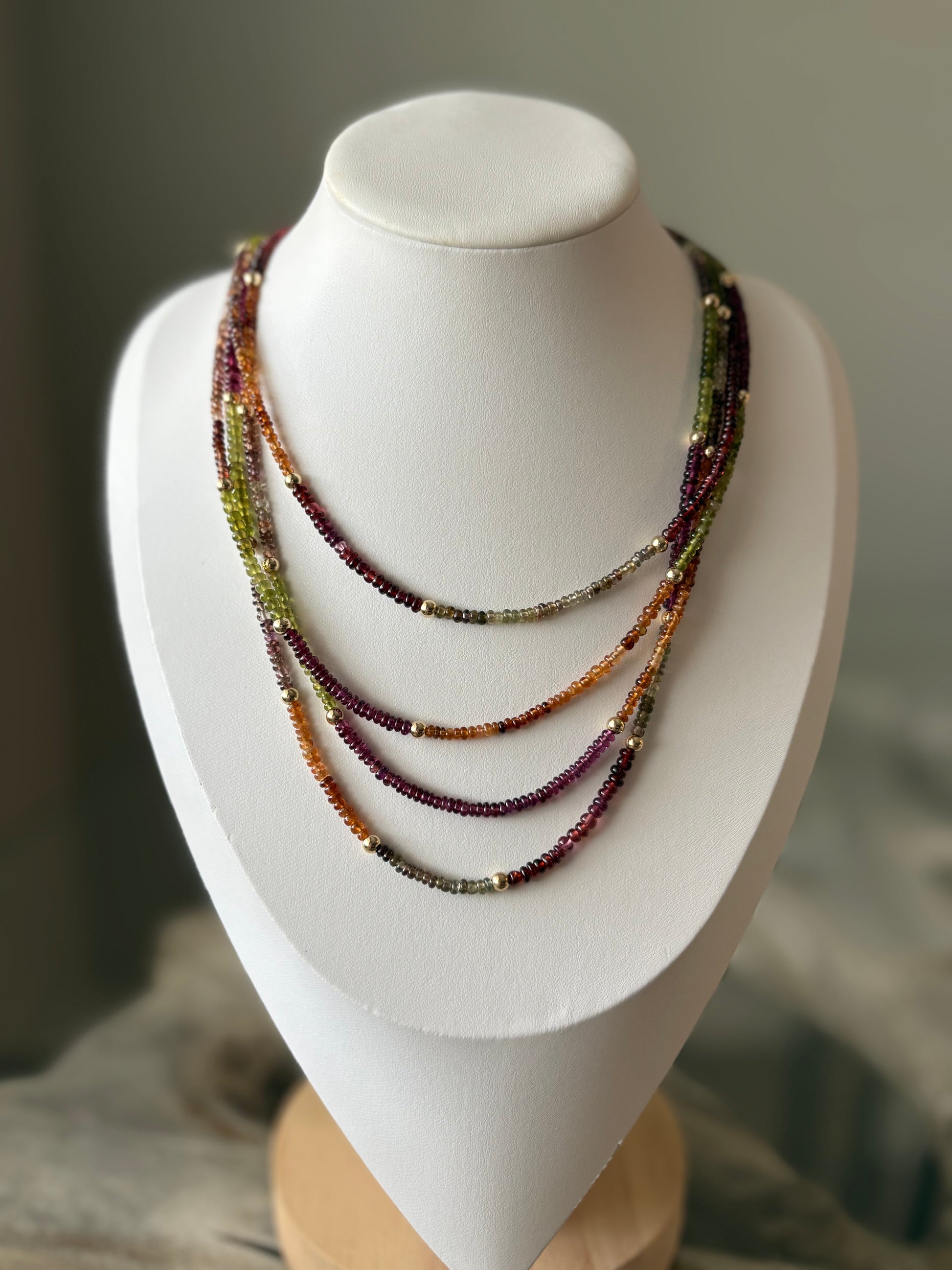 Sapphire Necklace with multiple strands of small, colorful beads in green, purple, and orange hues