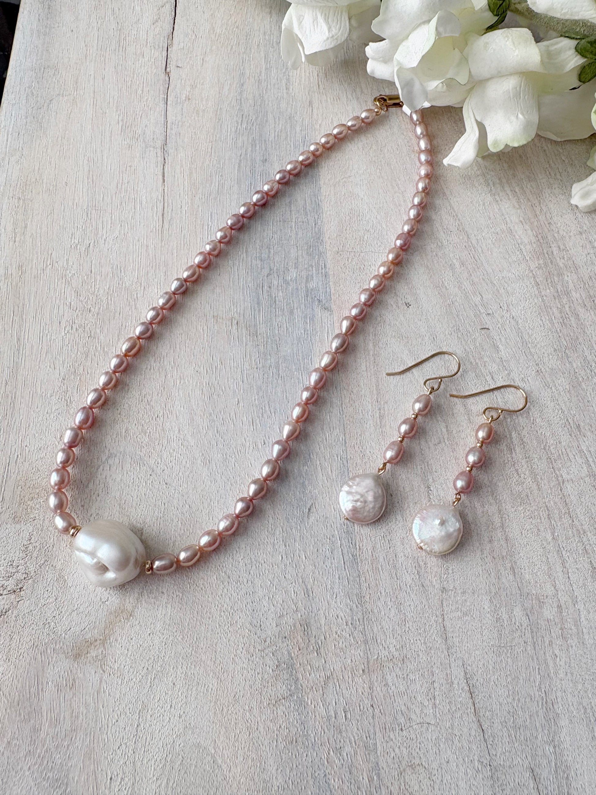 Mauve Pearl Earrings and matching necklace on a white wooden surface