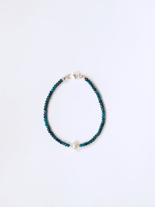 Blue beaded bracelet on a light blue background