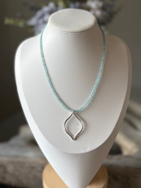 Necklace with a silver pendant on a white mannequin bust.