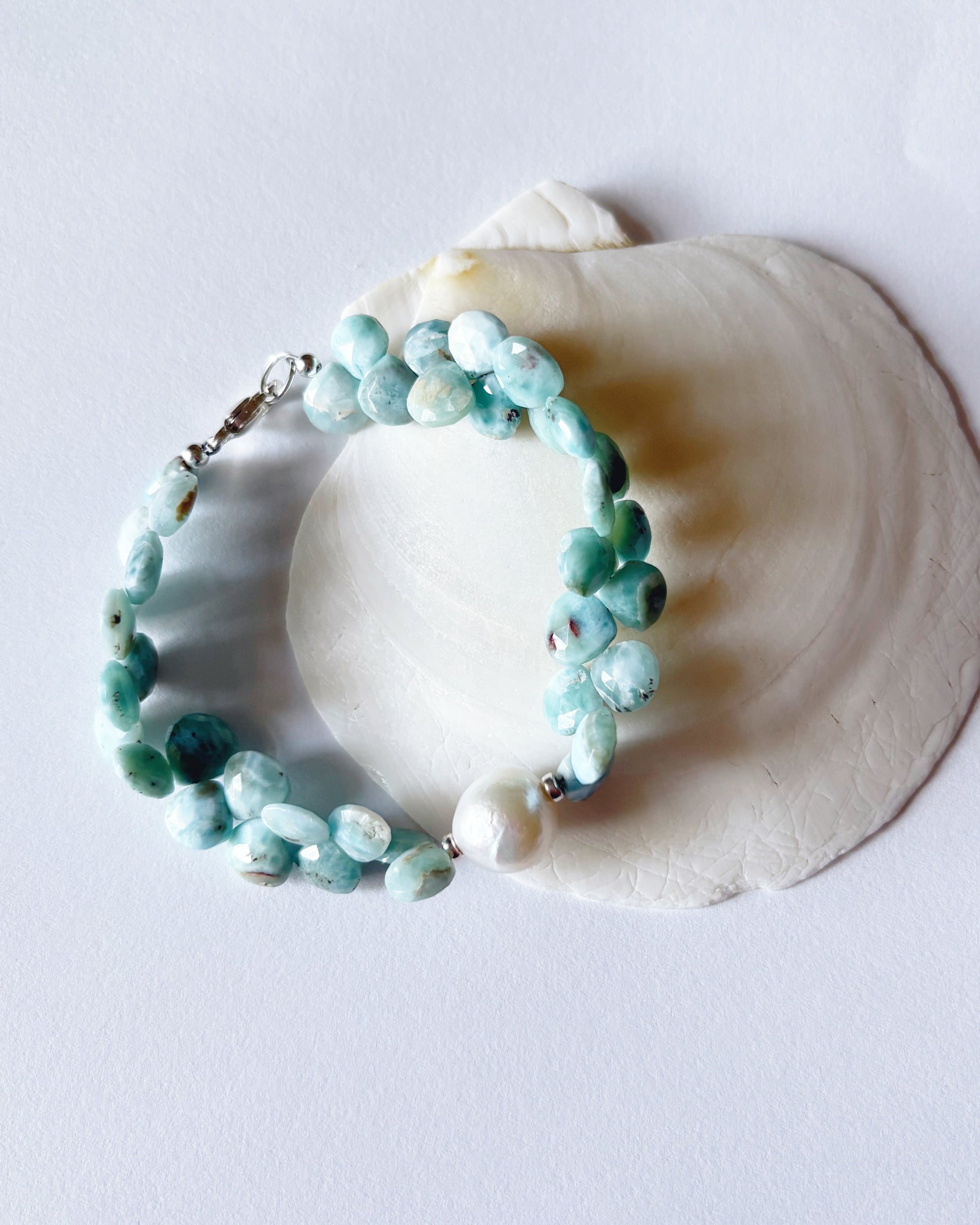 Turquoise beaded bracelet on a white shell against a light background