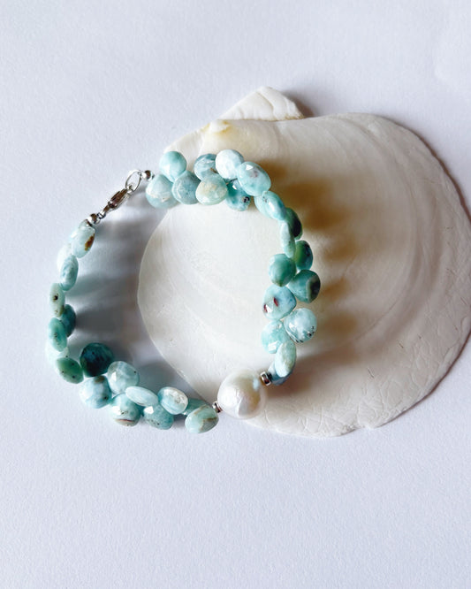 Turquoise beaded bracelet on a white shell against a light background