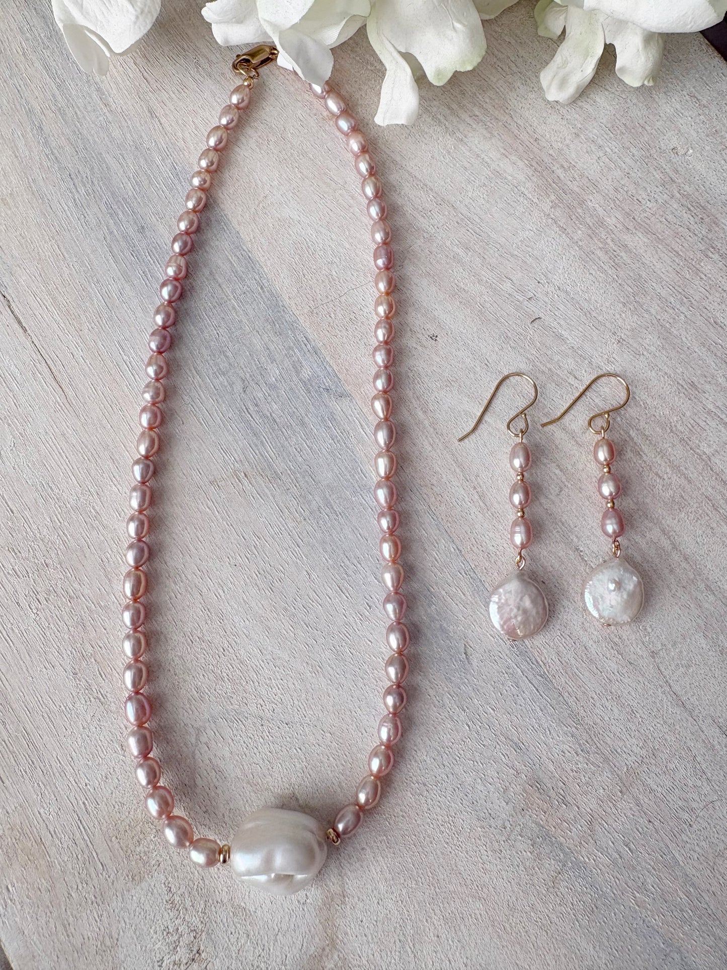 Mauve Pearl Earrings and matching necklace on a light wooden surface