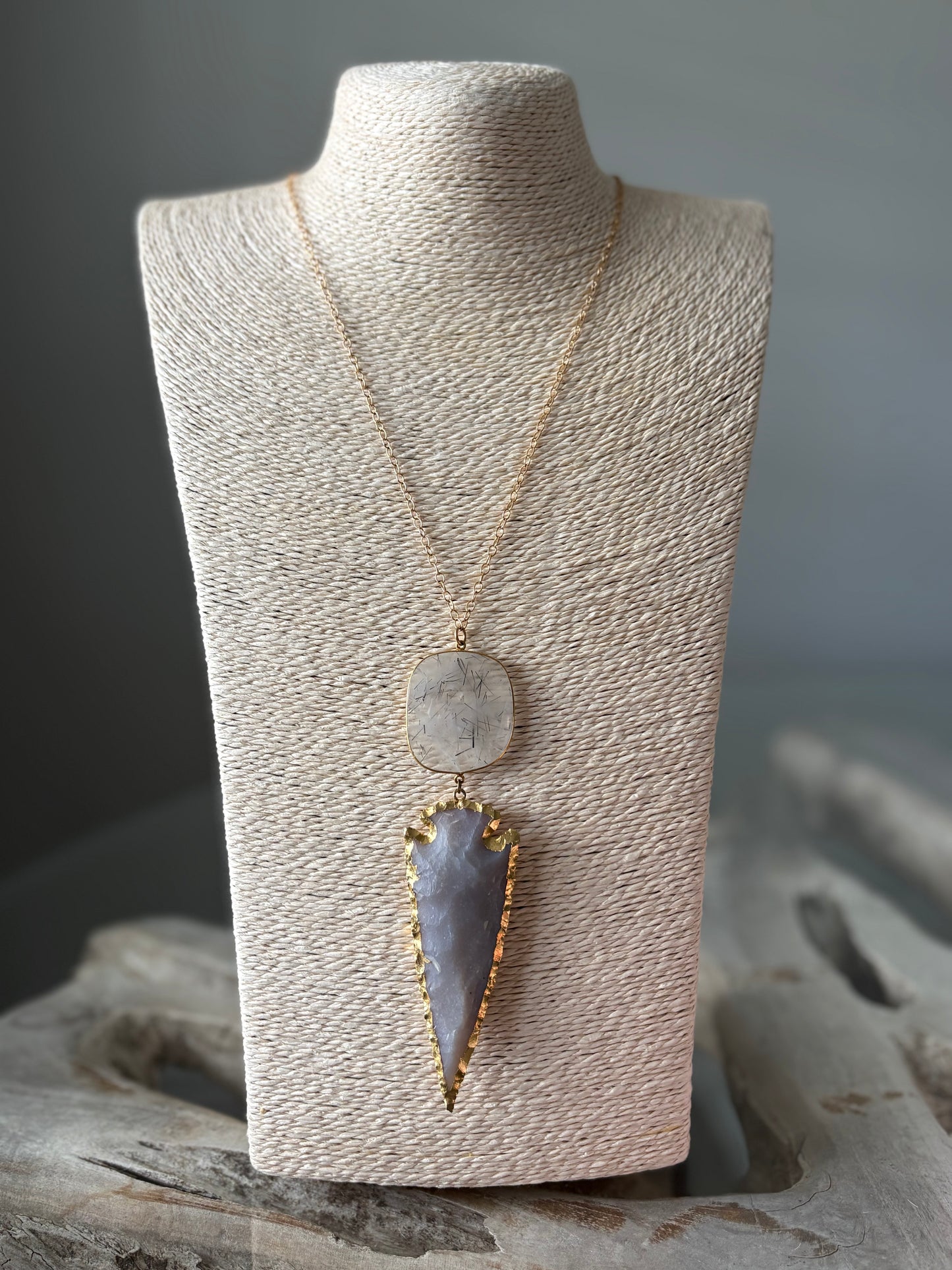 Arrow and Rutilated Quartz Necklace with gold chain and settings on a light brown display bust