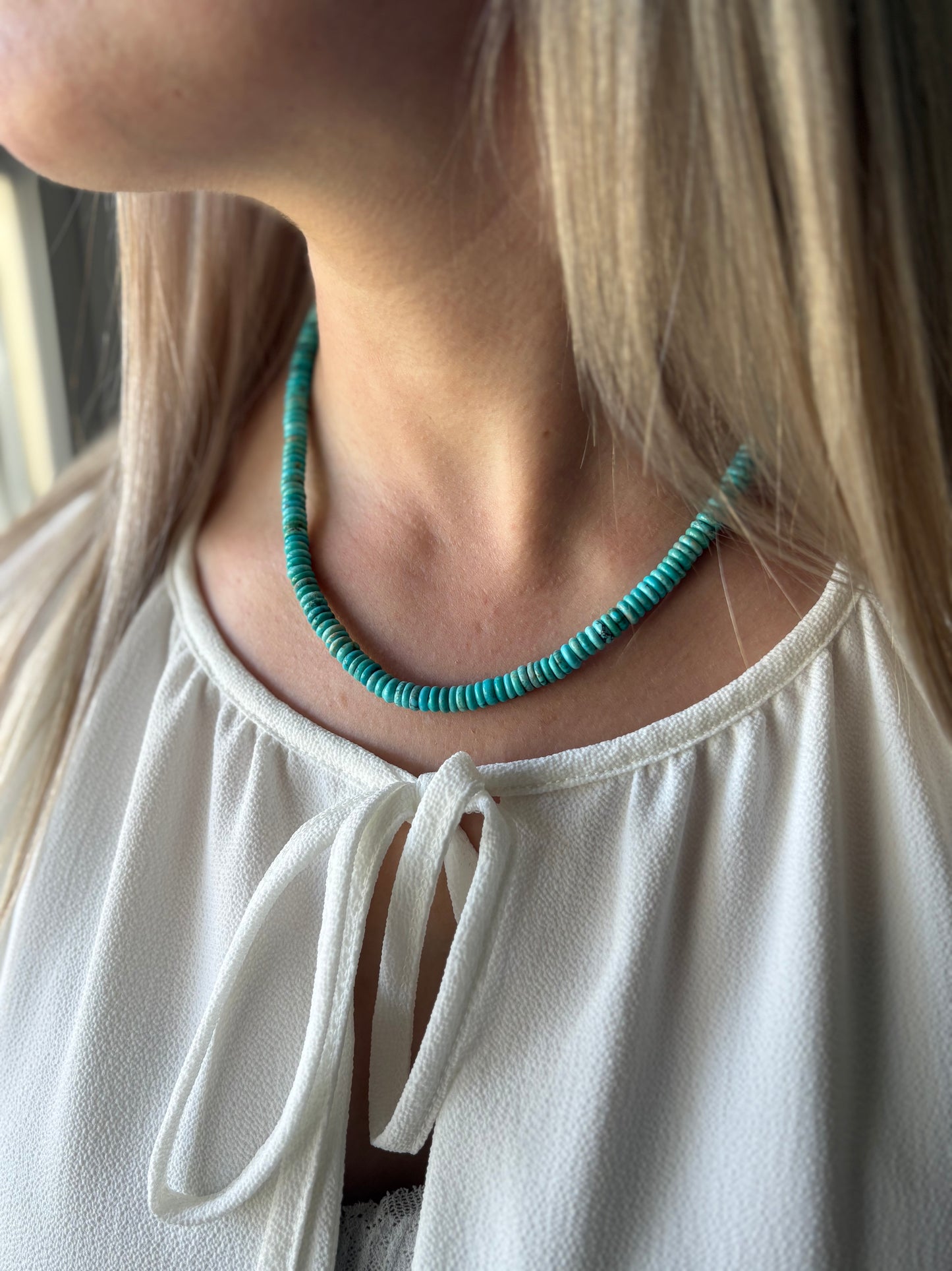 Turquoise Necklace with small flat beads on a person with blonde hair and a white top