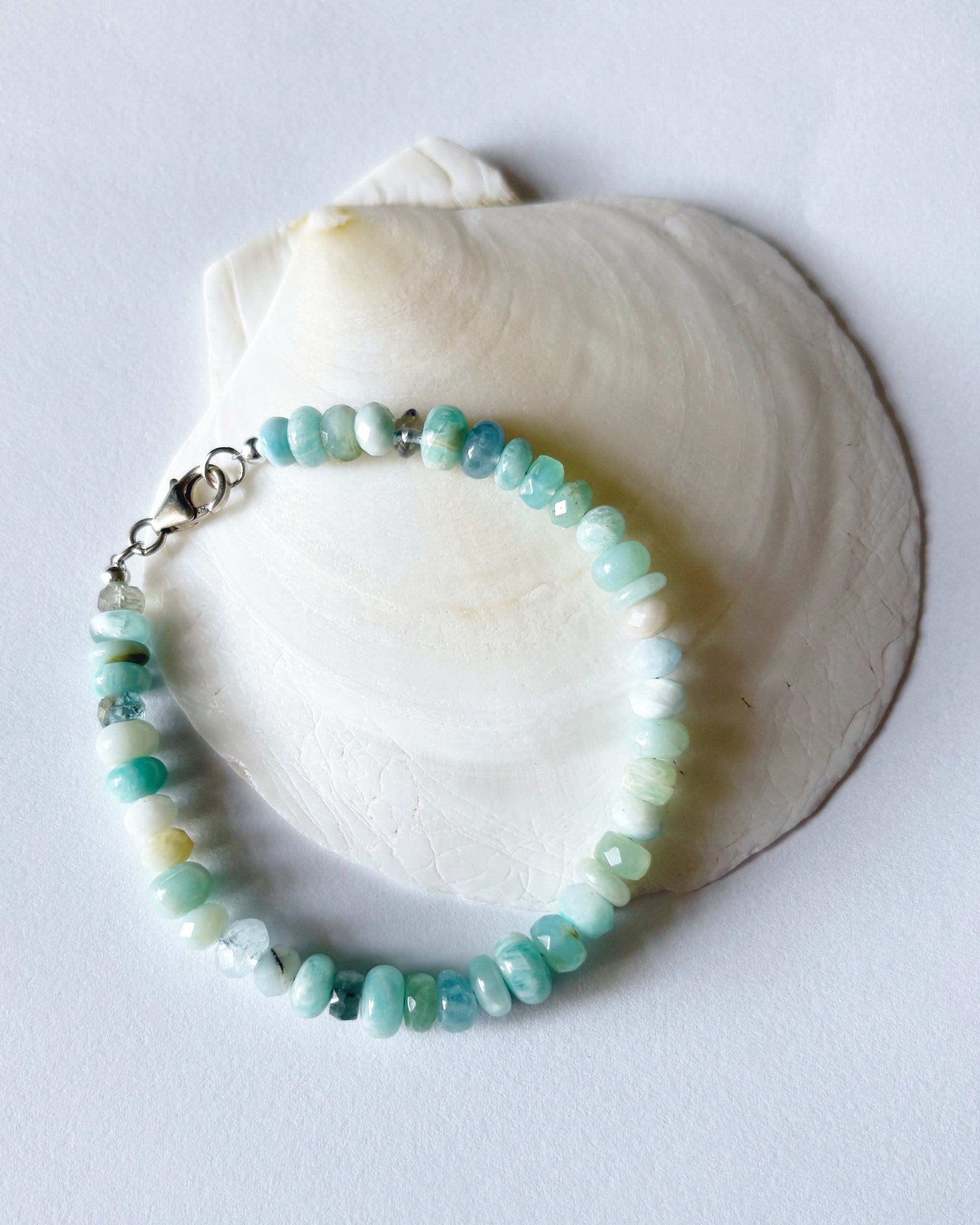 Turquoise beaded bracelet on a white shell against a light gray background