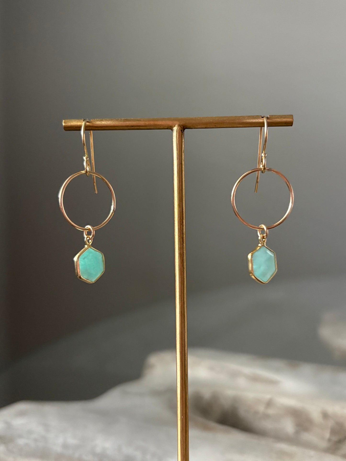 Gold earrings with turquoise stones on a gray background