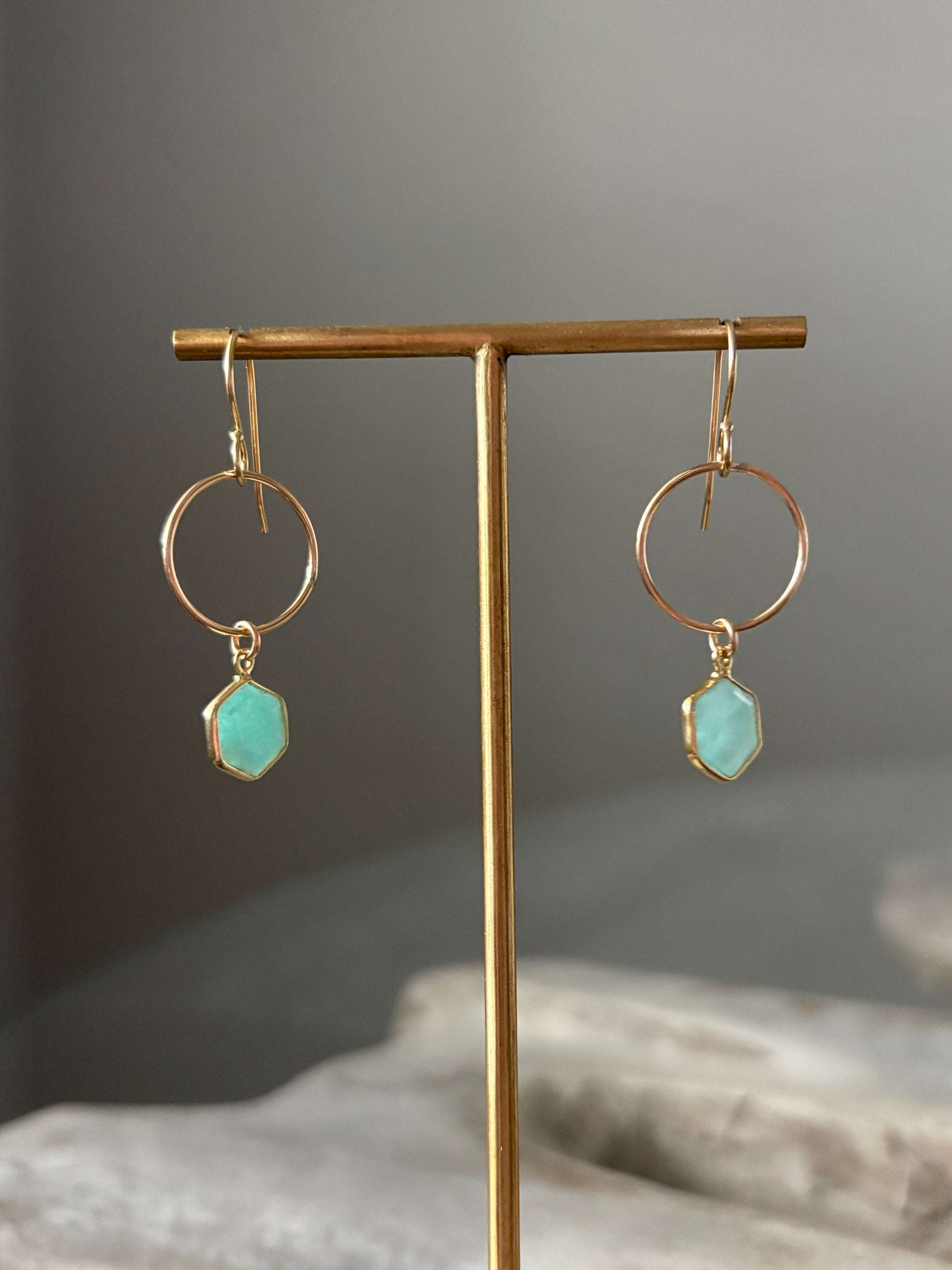 Gold earrings with turquoise stones on a gray background