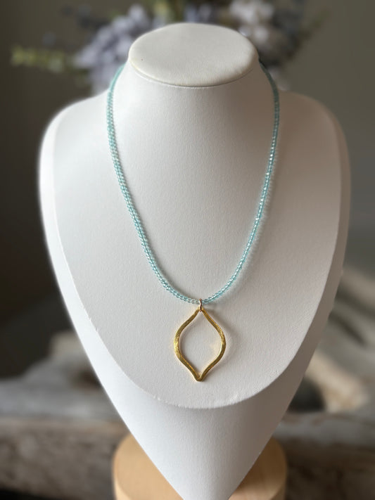 Necklace with a gold pendant on a white mannequin bust.