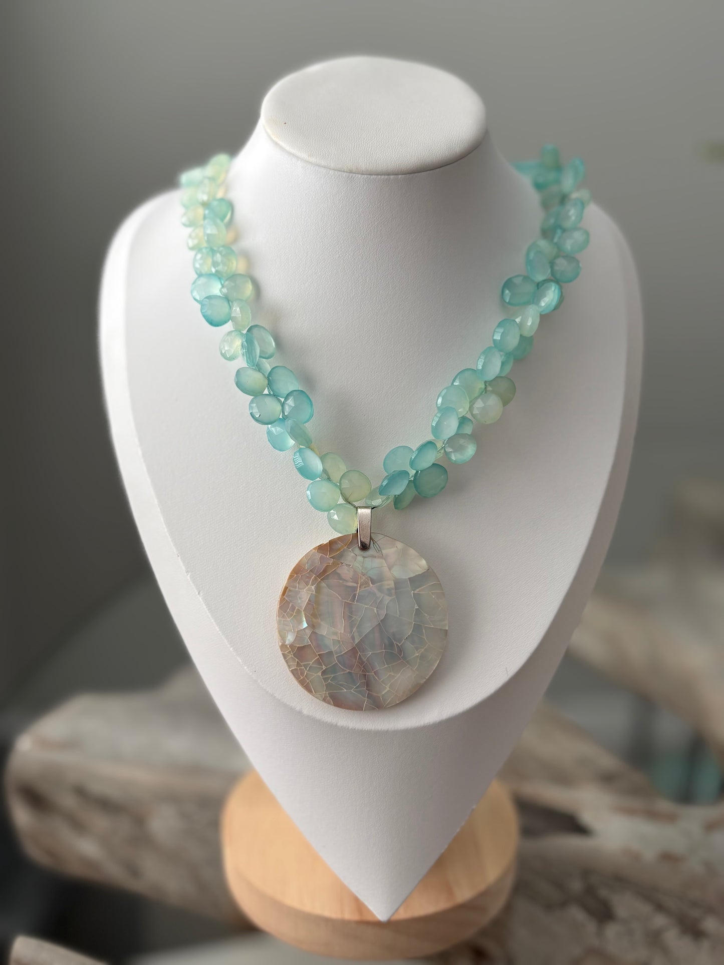 Necklace with a large round pendant on a white mannequin bust.