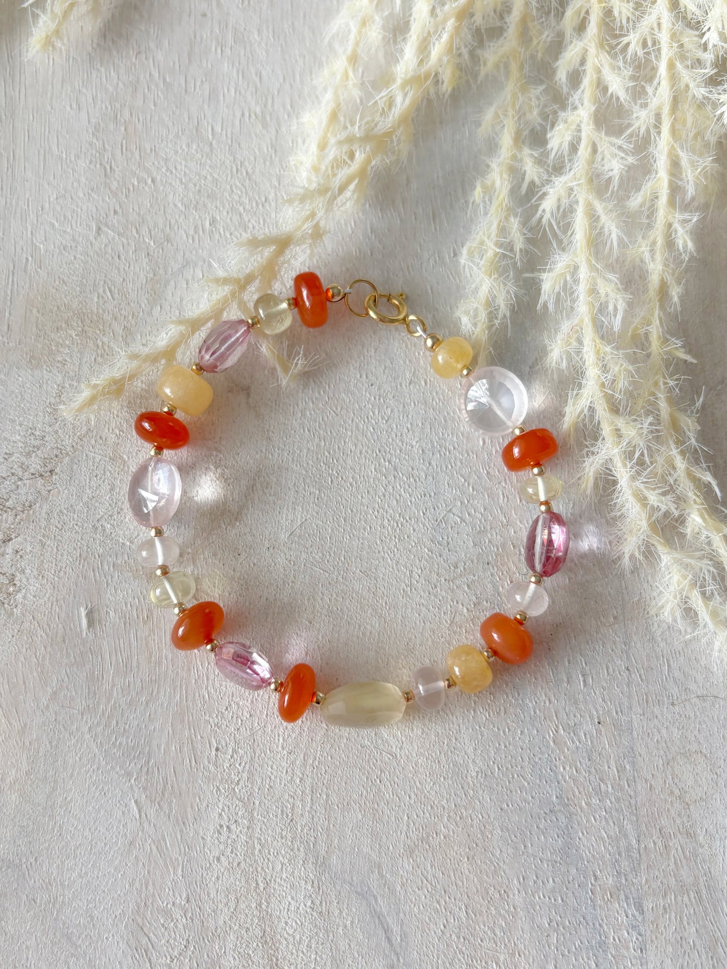 Multi Gemstone Bracelet 7.25 with gold clasp and various colored beads on a white textured surface